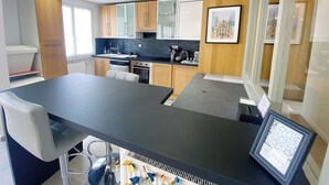 A modern kitchen with a central island, wooden cabinets, and a black countertop. - At Clém's, 8 people, private garage, wifi + Netflix (Reims)