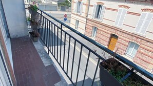 A balcony with a metal railing, potted plants, and a view of neighboring buildings. - At Clém's, 8 people, private garage, wifi + Netflix (Reims)