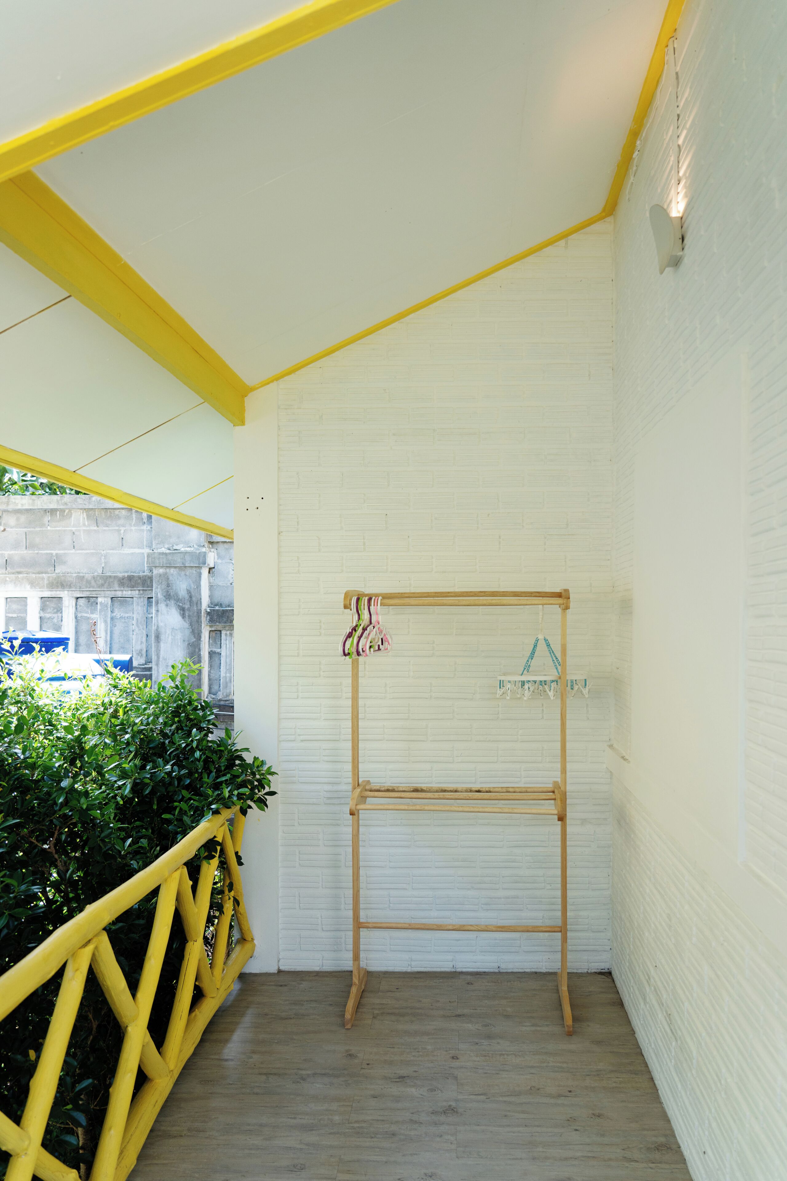Una habitación con pared de ladrillo blanco, escalera de madera y barandilla amarilla.