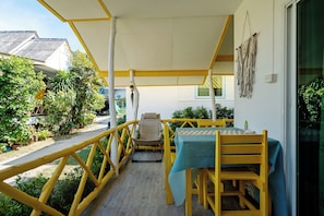 Un espace extérieur abrité, avec une table et des chaises, une rambarde et une vue sur la rue.
