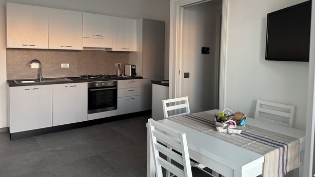A modern kitchen with white cabinets, a gas stove, and a dining area with a table and chairs.