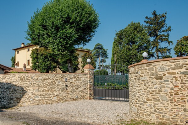 A stone wall, a gated entrance, and a building with a tiled roof.