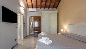 Una habitación de hotel con cama, televisor, armario y puerta que da a un baño.