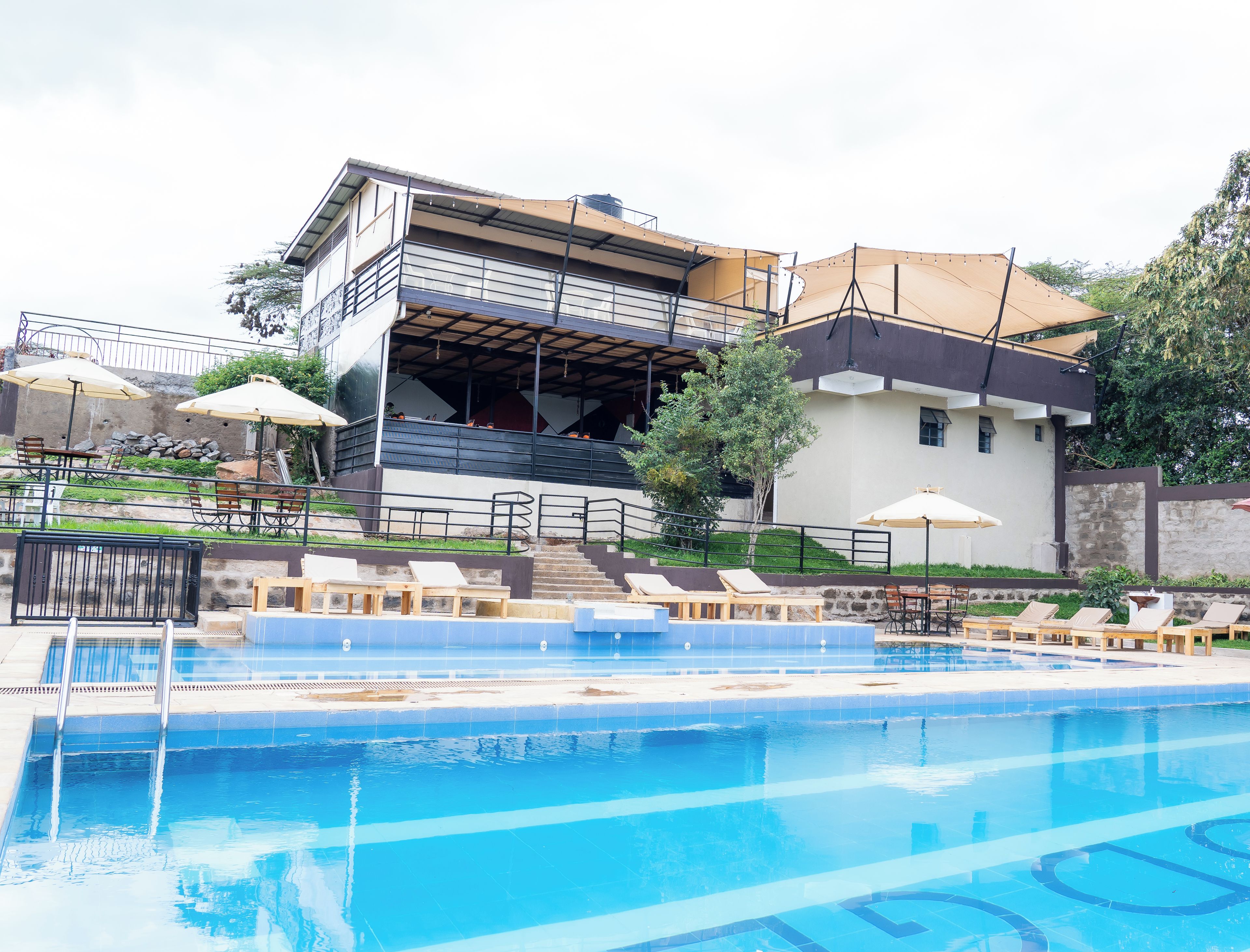 A modern hotel with a swimming pool, outdoor seating, and a covered area.
