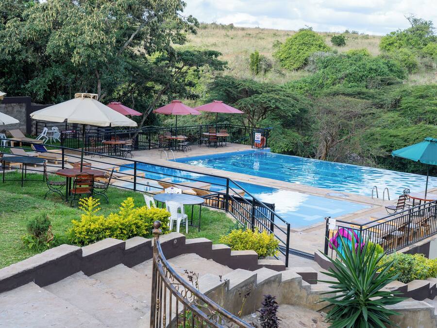 A pool area with lounge chairs, umbrellas, and a staircase leading to a deck.