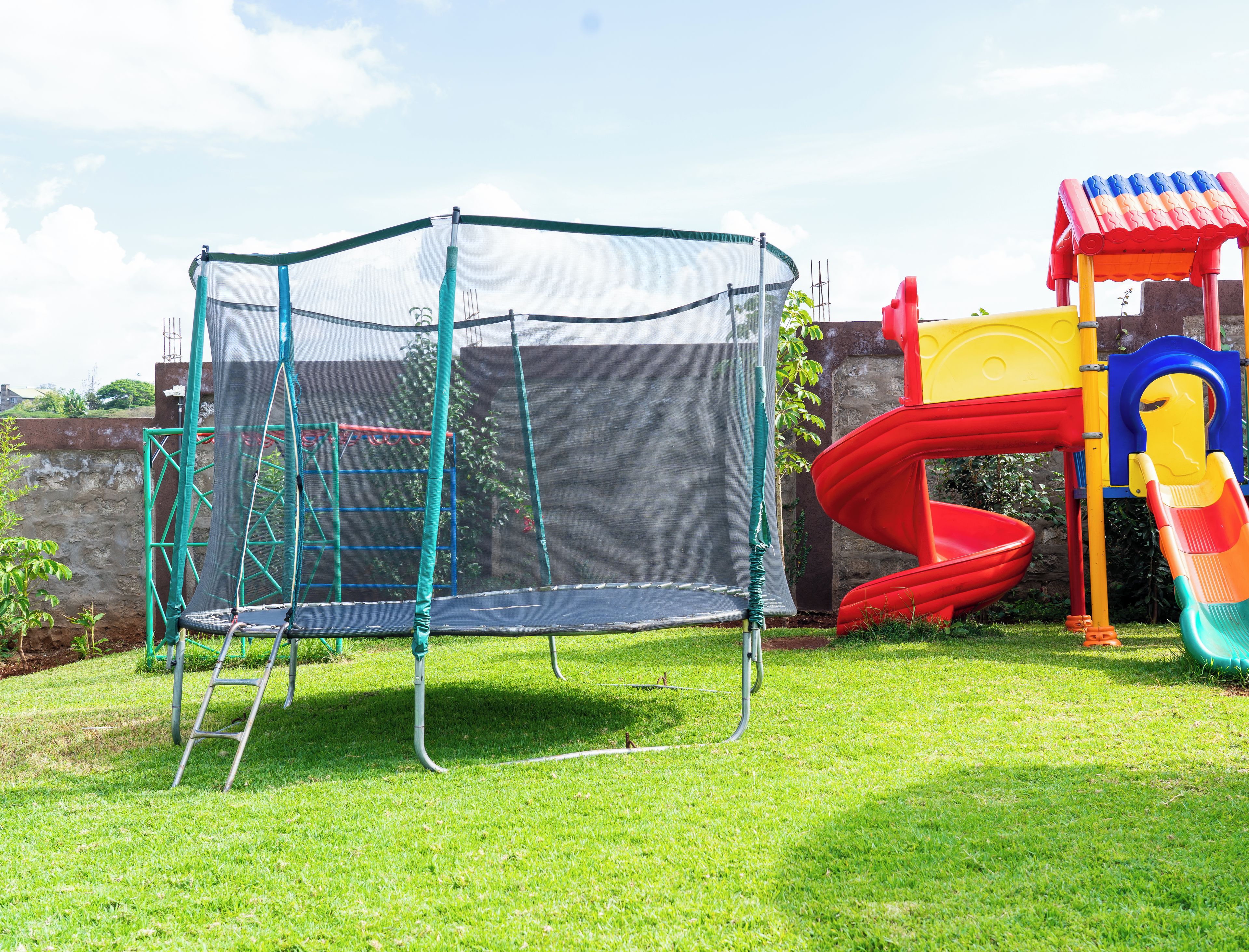 A playground with a trampoline, slide, and climbing structure.