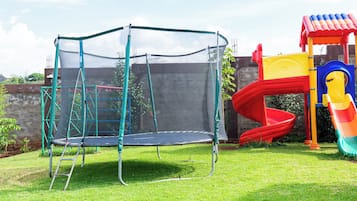 A playground with a trampoline, slide, and climbing structure.