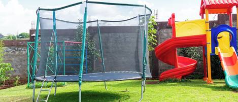A playground with a trampoline, slide, and climbing structure.