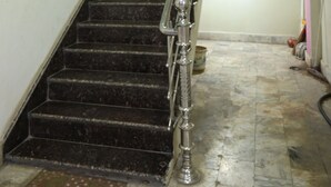 A staircase with a metal railing, a potted plant, and a trash bin. - Gauri Shankar P Guest house (Varanasi)