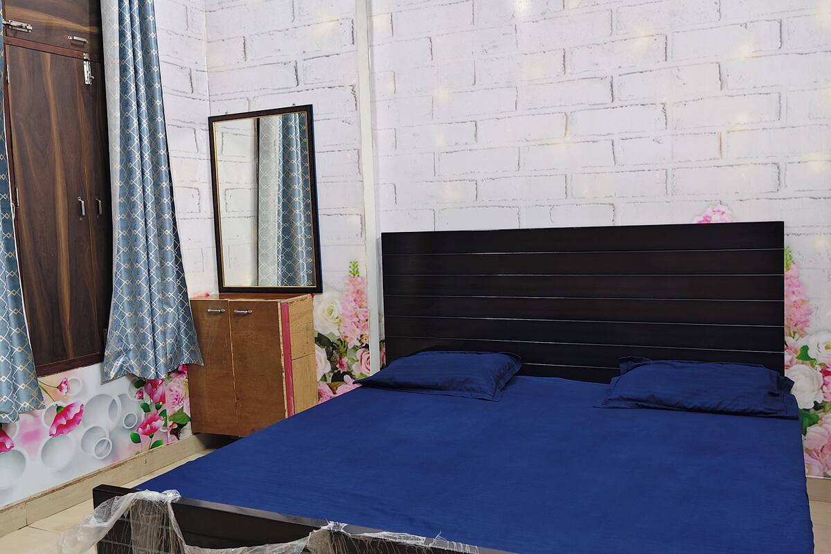 A bedroom with a bed, wooden wardrobe, and a mirror.