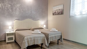 A bedroom with two beds, bedside lamps, a nightstand, a painting on the wall, and a window with curtains. - Room 'Il Borghetto Lavanda' with Shared Garden, Wi-Fi and Air Conditioning (Borgo San Lorenzo)
