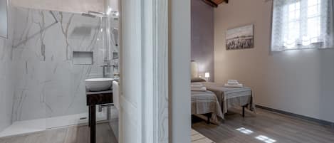 Un baño con pared de mármol, lavamanos y ducha.