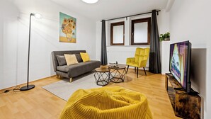 A modern living room with a sofa, yellow armchair, and a TV. - Cosy&Central, 500m from Main Station, Work&Stay (Wiesbaden)