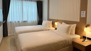 A hotel room with two beds, a TV, and a sign indicating free Wi-Fi. - Winston Hotel (Bangkok)