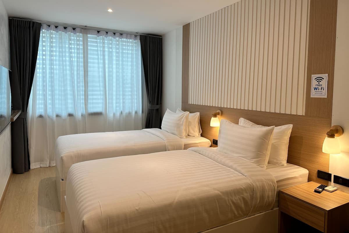 A hotel room with two beds, a TV, and a sign indicating free Wi-Fi.
