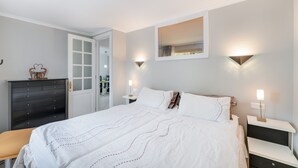Een slaapkamer met een bed, nachtkastjes, een dressoir en een spiegel.