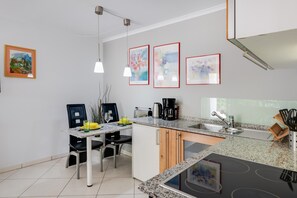 Una cocina moderna con comedor, encimeras de granito, horno empotrado y cafetera.