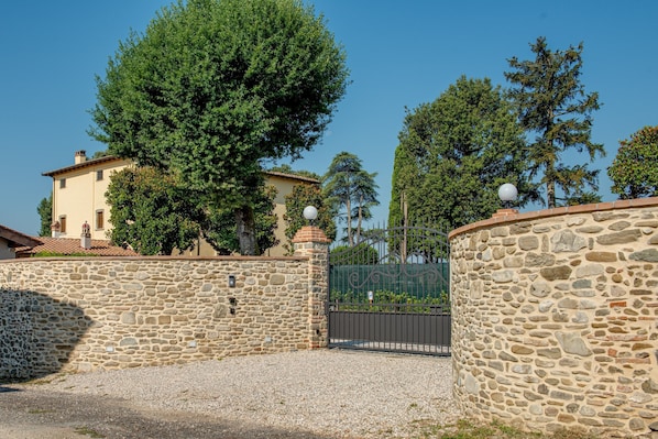 A stone wall, a gated entrance, and a building with a tiled roof.