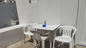 A small outdoor patio with a white table and two white plastic chairs.