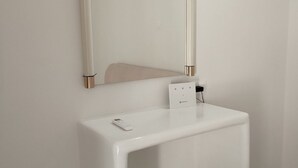 A white bathroom vanity with a mirror and a small electrical outlet.