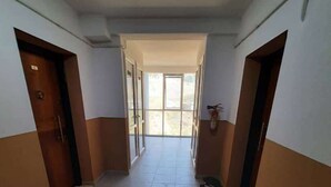 Un pasillo con puertas a ambos lados que conduce a un espacio luminoso con ventanas.