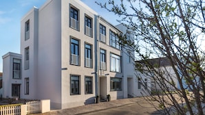 A modern multi-story building with a flat facade, large windows, and a white picket fence in front. - // KÖNIG APARTMENTS - APARTMENT 3 // (Norderney)