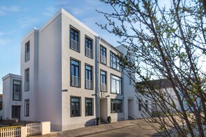 A modern multi-story building with a flat facade, large windows, and a white picket fence in front. - // KÖNIG APARTMENTS - APARTMENT 3 // (Norderney)