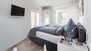 A bedroom with a bed, a desk, a chair, a TV, and a window. - // KÖNIG APARTMENTS - APARTMENT 3 // (Norderney)