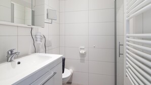 A modern bathroom with a white sink, mirror, and toilet. - // KÖNIG APARTMENTS - APARTMENT 3 // (Norderney)