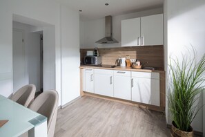 Een moderne keuken met witte kasten, een magnetron en een waterkoker op het aanrecht.