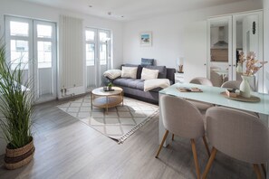 A modern living room with a sofa, coffee table, and dining area. - // KING APARTMENTS - APARTMENT 5 // (Norderney)