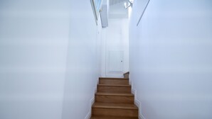 Un escalier en bois, avec des murs blancs et une porte en haut.