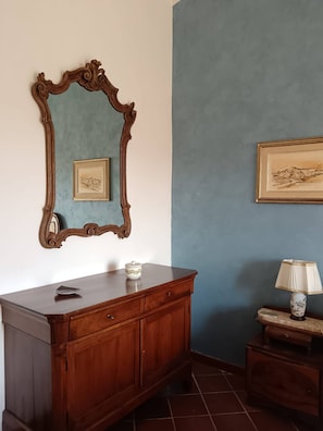 A room with a wooden dresser, a mirror, a framed picture, and a lamp on a side table.