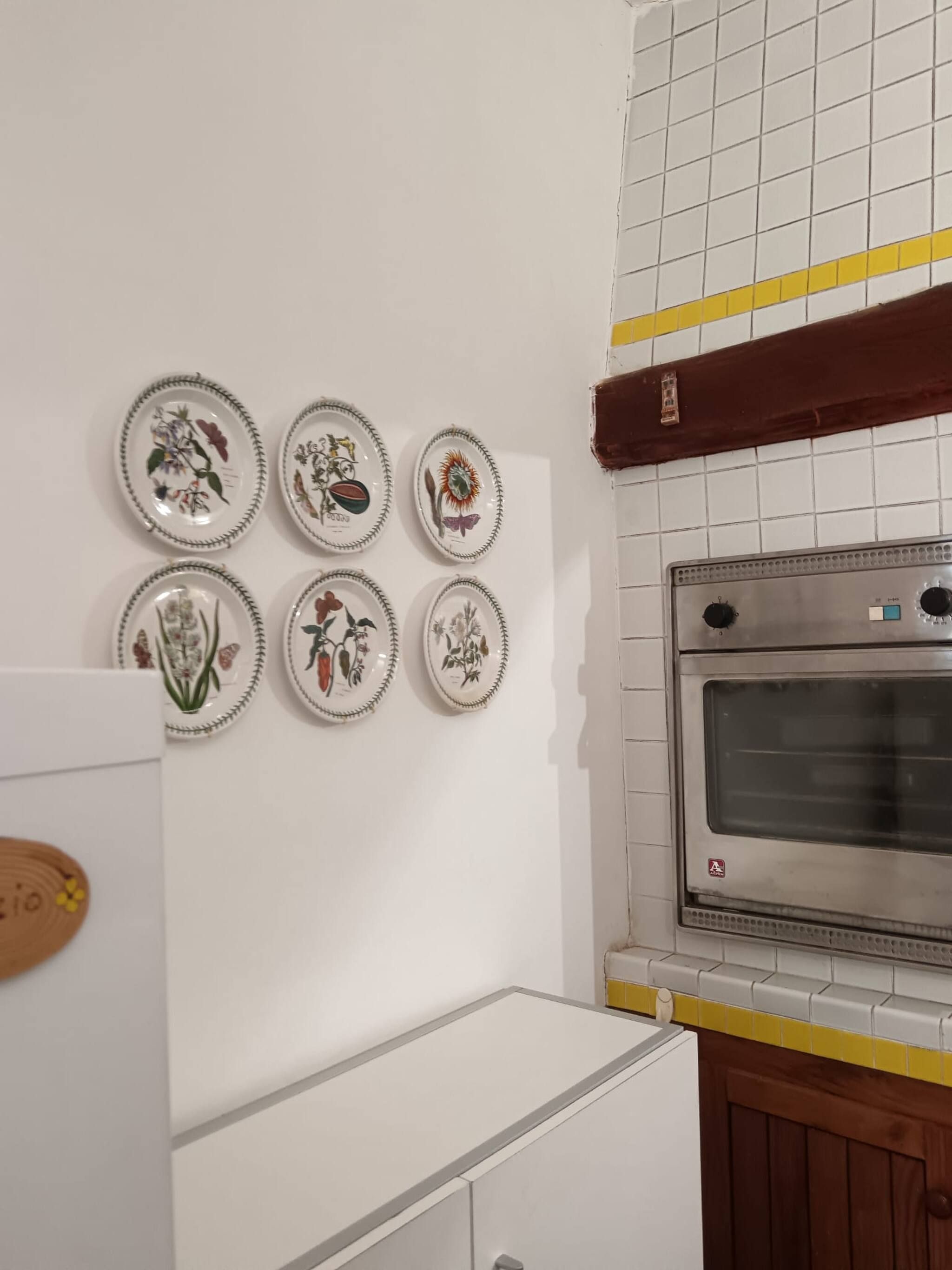 A kitchen with a refrigerator, oven, and six decorative plates on the wall.