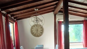 A dining area with a wooden ceiling, a round wall clock, white chairs, and red curtains. - Poggio Bassotto, Your Peaceful Retreat Near the Heart of Rome (Sacrofano)