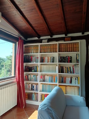 A cozy reading nook with a white sofa and a large bookshelf filled with books. - Poggio Bassotto, Your Peaceful Retreat Near the Heart of Rome (Sacrofano)