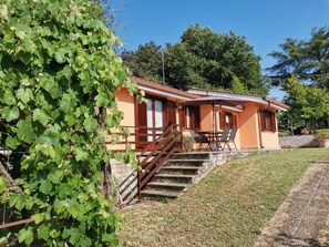 A two-story house with a staircase leading to the upper floor, a patio with outdoor seating, and a garden area with a pergola. - Poggio Bassotto, Your Peaceful Retreat Near the Heart of Rome (Sacrofano)