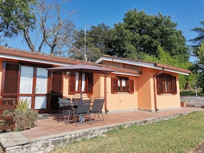 A two-story house with a patio, wooden shutters, and a table with chairs.