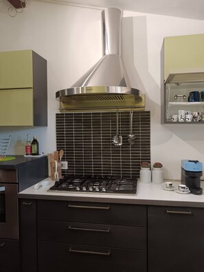 A modern kitchen with a gas stove, stainless steel hood, and a tiled backsplash. - Poggio Bassotto, Your Peaceful Retreat Near the Heart of Rome (Sacrofano)