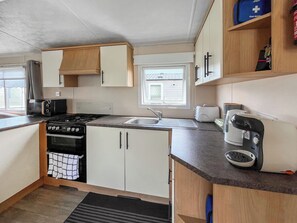 A compact kitchen with a stove, sink, and toaster.