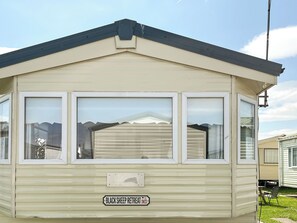 A mobile home with a garage door, a nameplate, and a small porch.