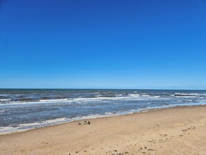 A beach with a clear sky, waves, and a sandy shore.