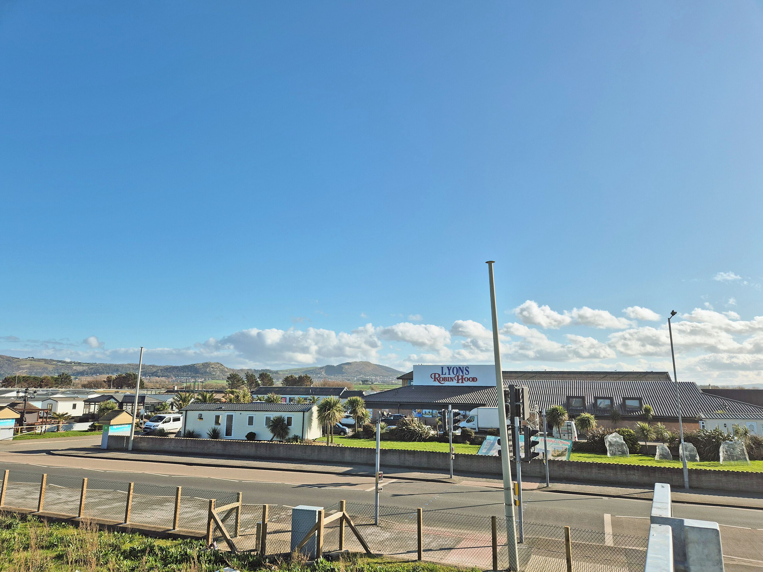 A coastal view with a sign for 'LYONS Robin Hood' and a building with a corrugated metal roof.