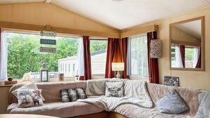A cozy living room with a sectional sofa, a round coffee table, and a large window with curtains. - 3 bedroom accommodation in Tosside, near Settle (Tosside, near Settle)