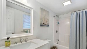 A bathroom with a white sink, a mirror, a toilet, and a shower curtain. - Cozy Studio Steps from Beach & Pier Village! (St Simons Island)