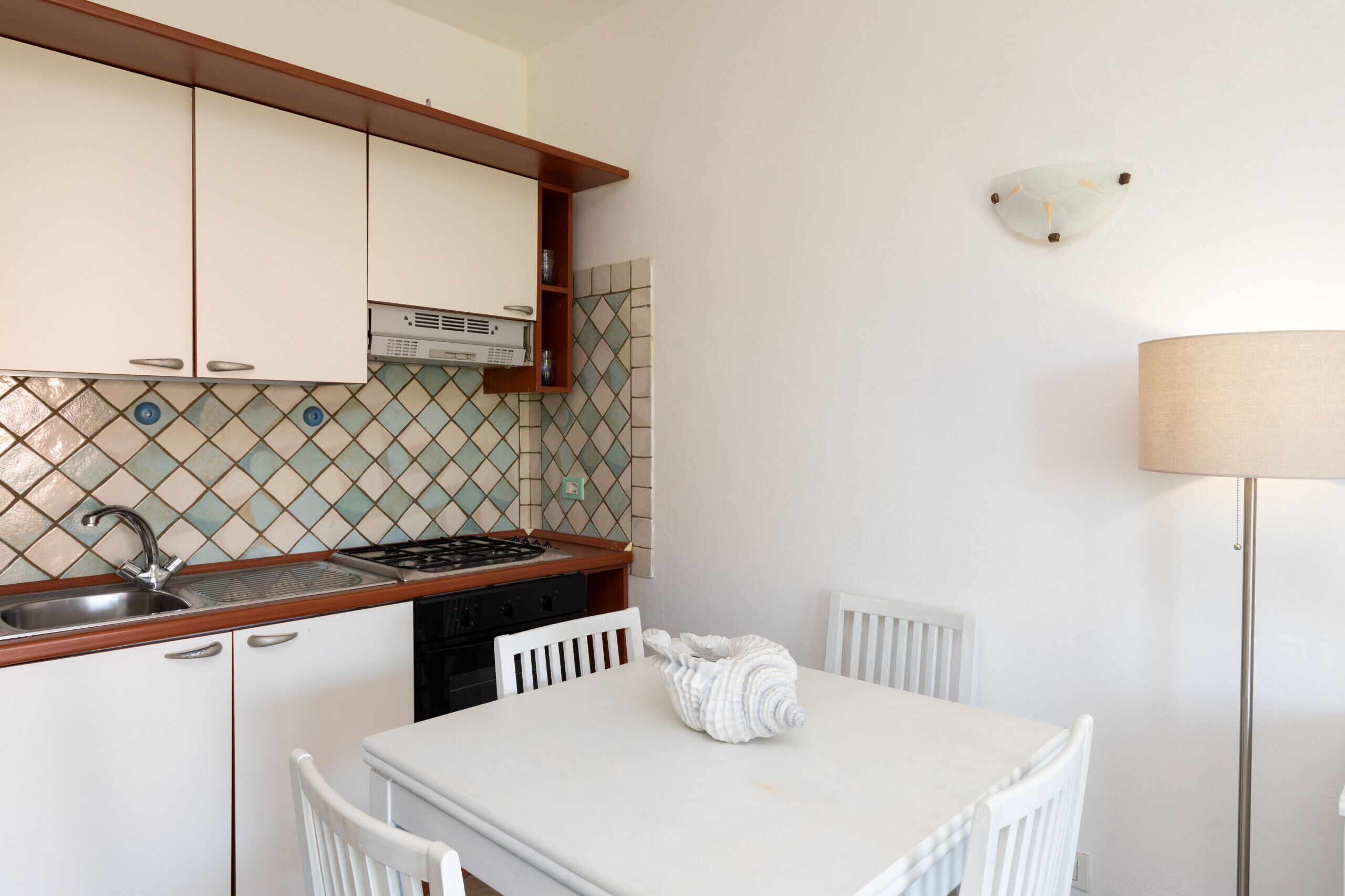 A kitchen with white cabinets, a tiled backsplash, a stove, and a dining table with chairs.