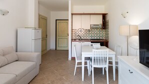 Une cuisine compacte avec un coin repas, un réfrigérateur blanc et un pare-feu en carreaux.