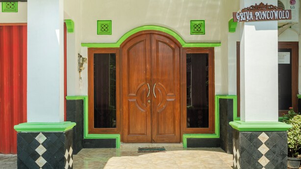 A wooden double door with a sign above it reading "GRIYA PONCOWOLO". - Griyaponcowolo (Yogyakarta)