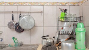 A kitchen with hanging pots, a dish rack, a kettle, a trash bin, and a green thermos. - Griyaponcowolo (Yogyakarta)