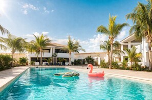 Une piscine bordée de palmiers et agrémentée d’un flotteur en forme de flamant rose.